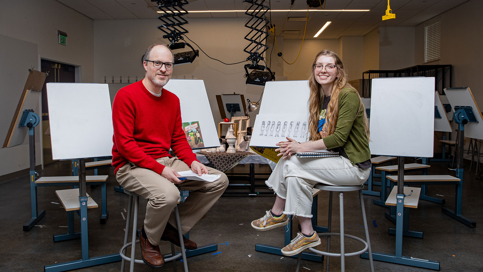 Studio art student sitting with professor in an art studio