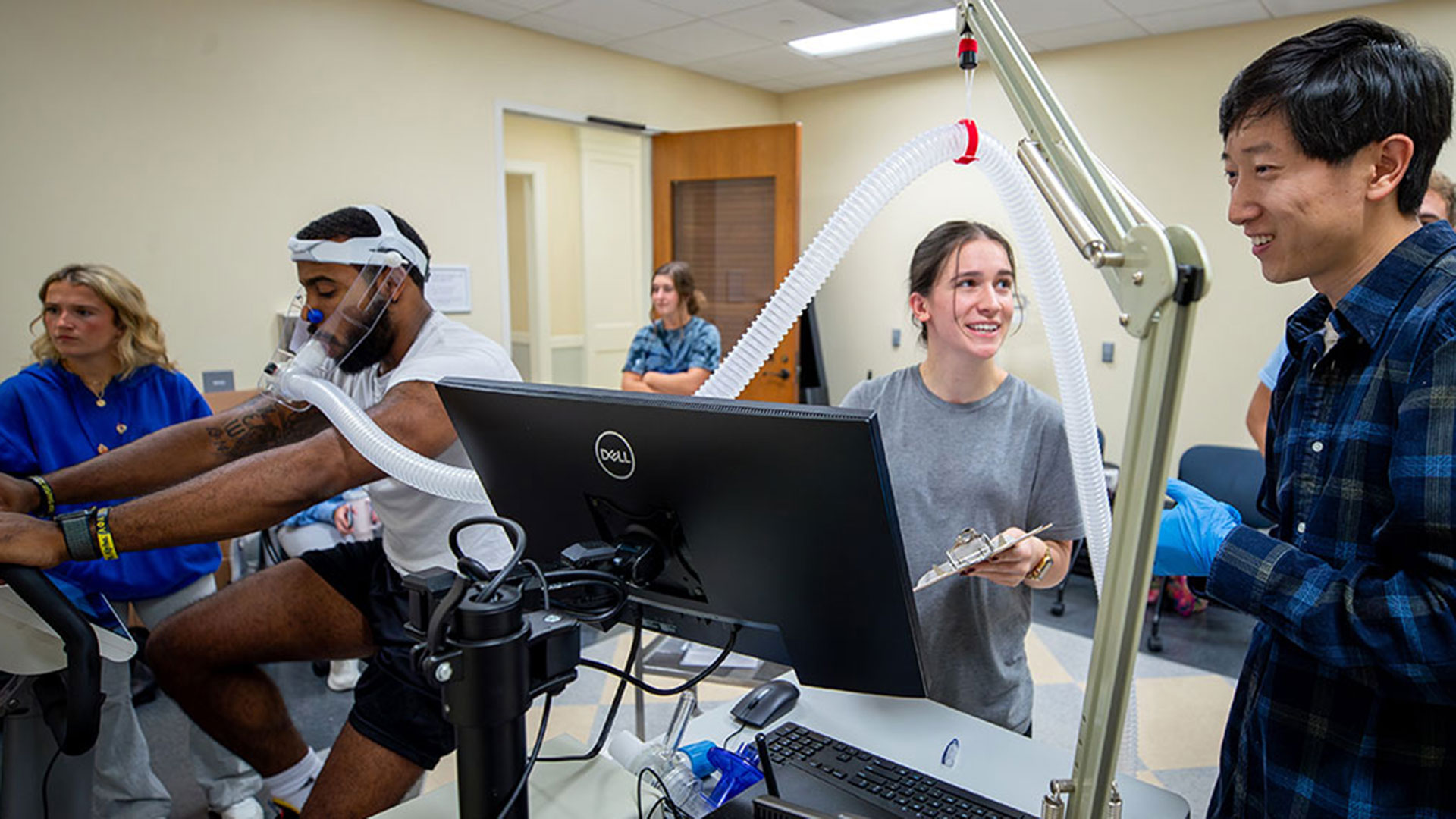 Students conducting a study of an athlete on a bicycle in the kinesiology lab