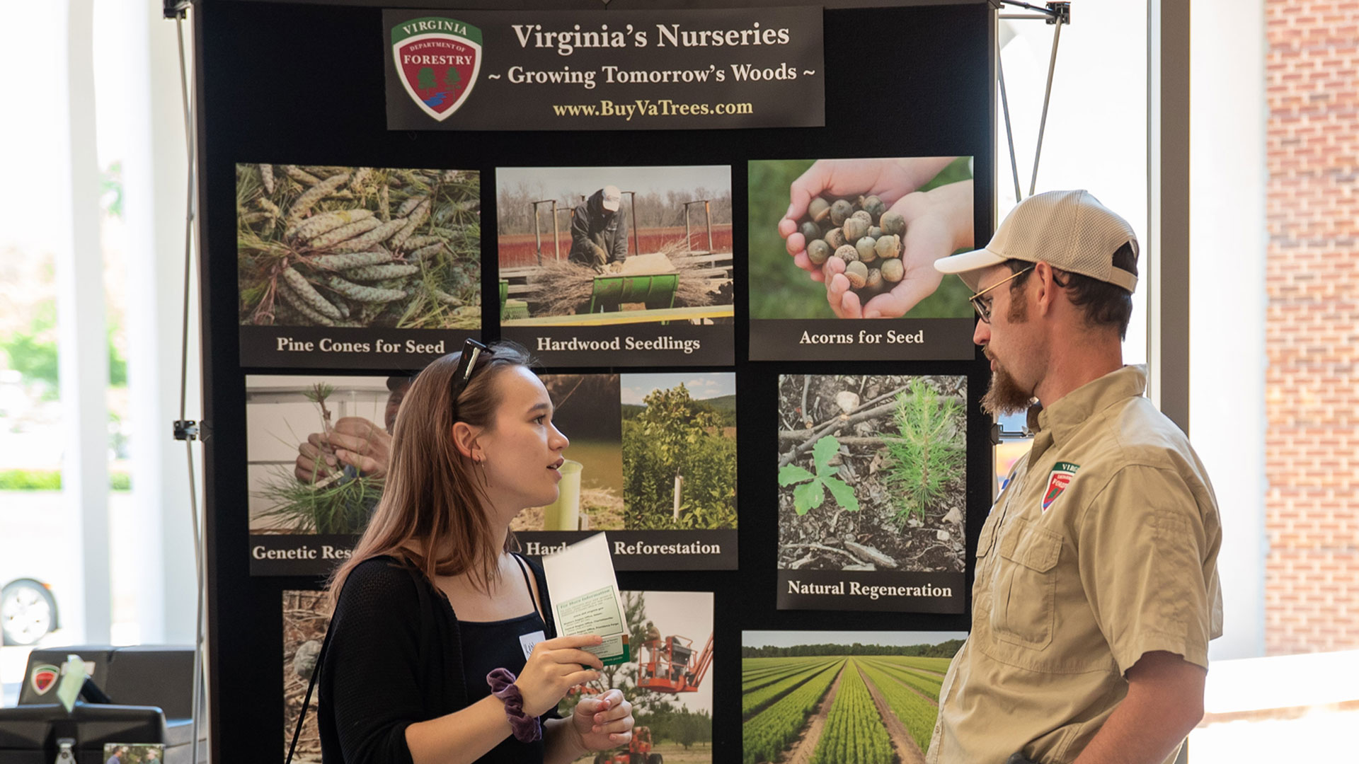 Student talking with a park ranger in front of an exhibit about Virginia's tree nurseries