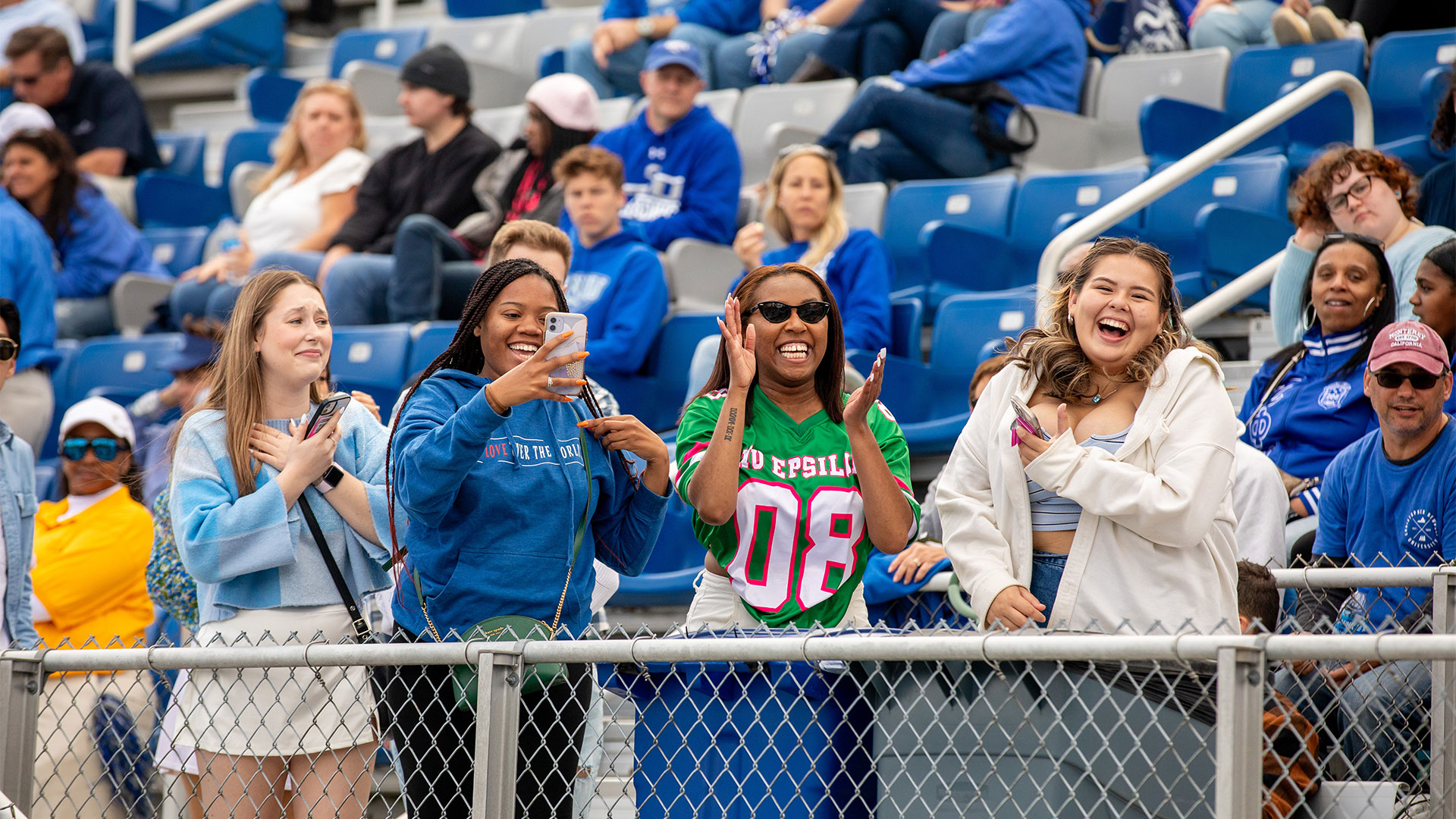 People cheering in the stands at a CNU homecoming football game.