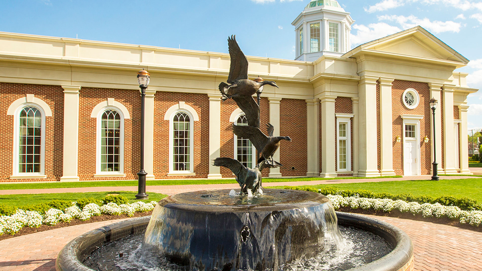 A fountain with a sculpture of 3 geese in flight stacked on top of one another