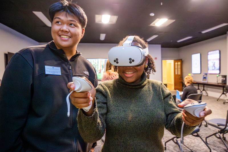 Two students smiling while using virtual reality headset.