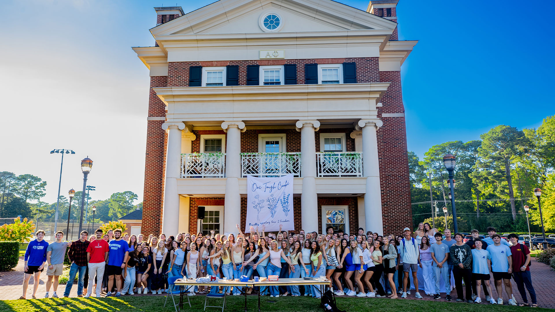 Alpha Phi poase for a group photo outside of Greek Village at their One Tough Cookie event.