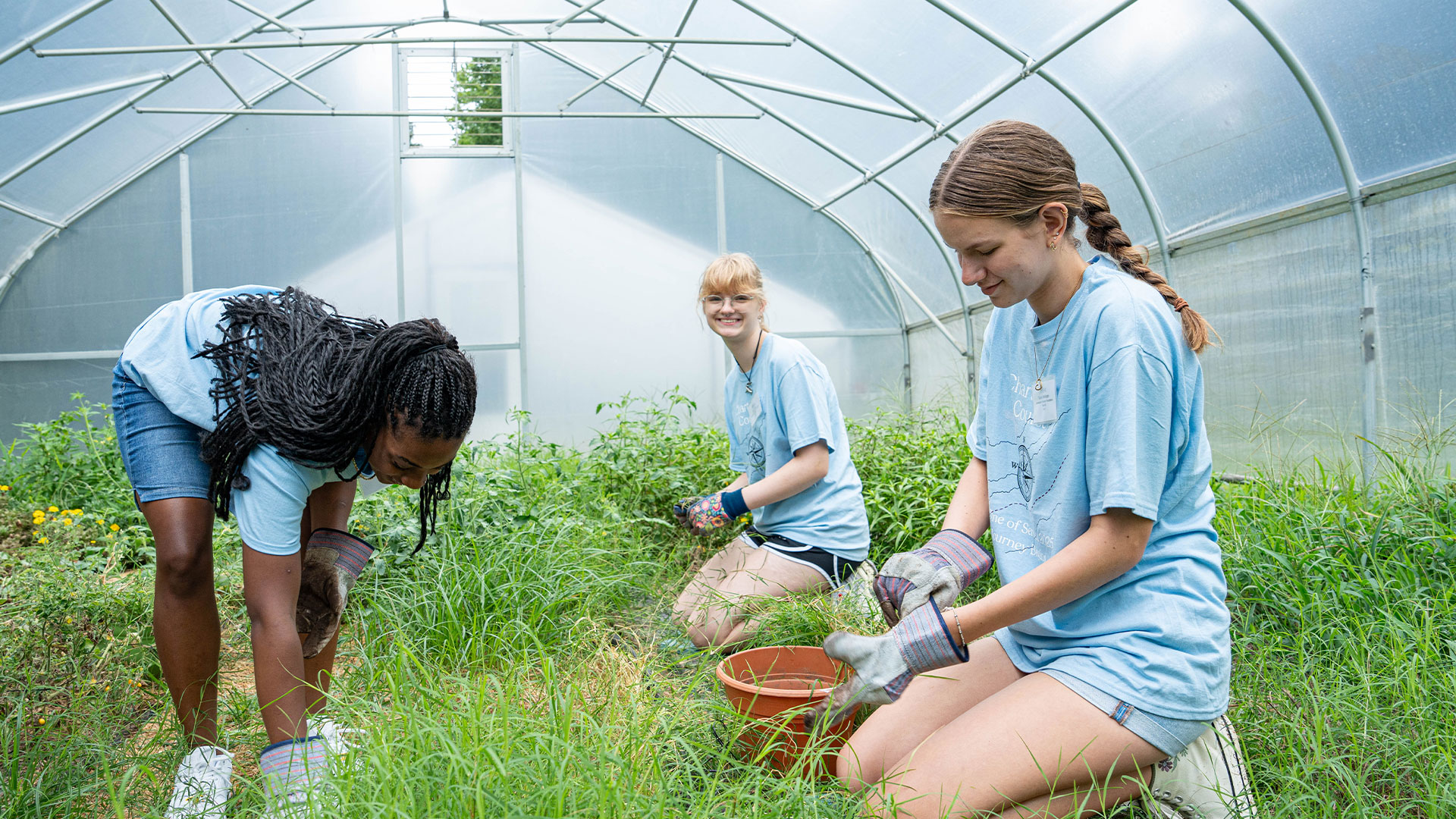 Three female students garden for Day One of Service.