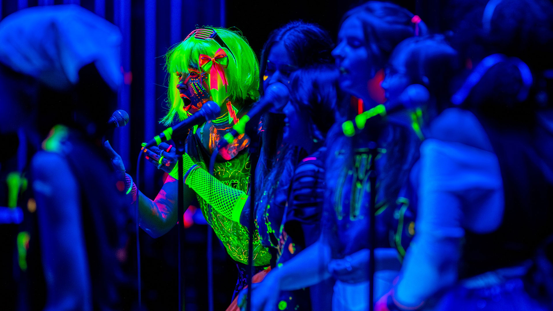 A group of performers sing on stage during Glow in the Darcapella.