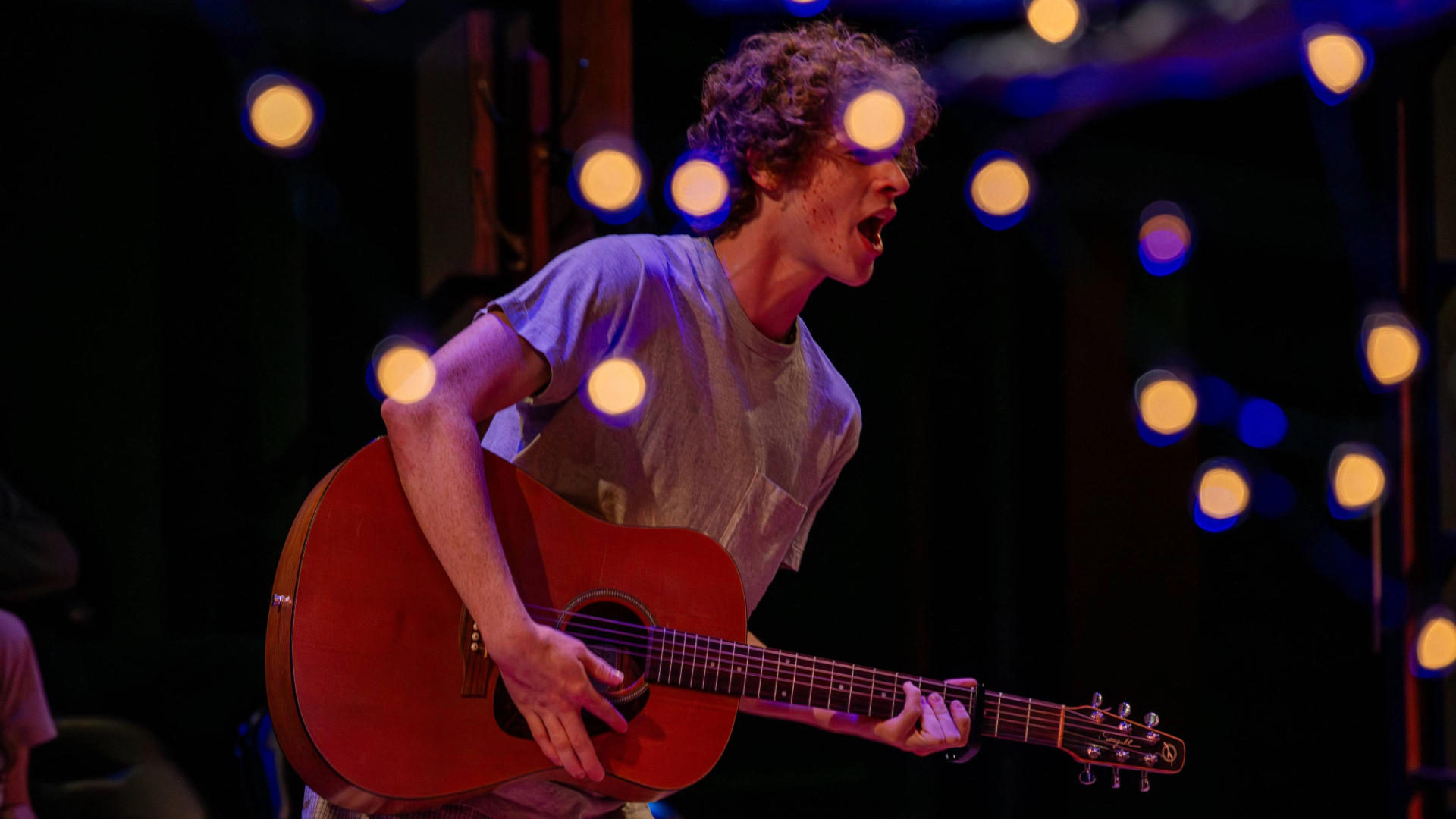 Student playing guitar on stage
