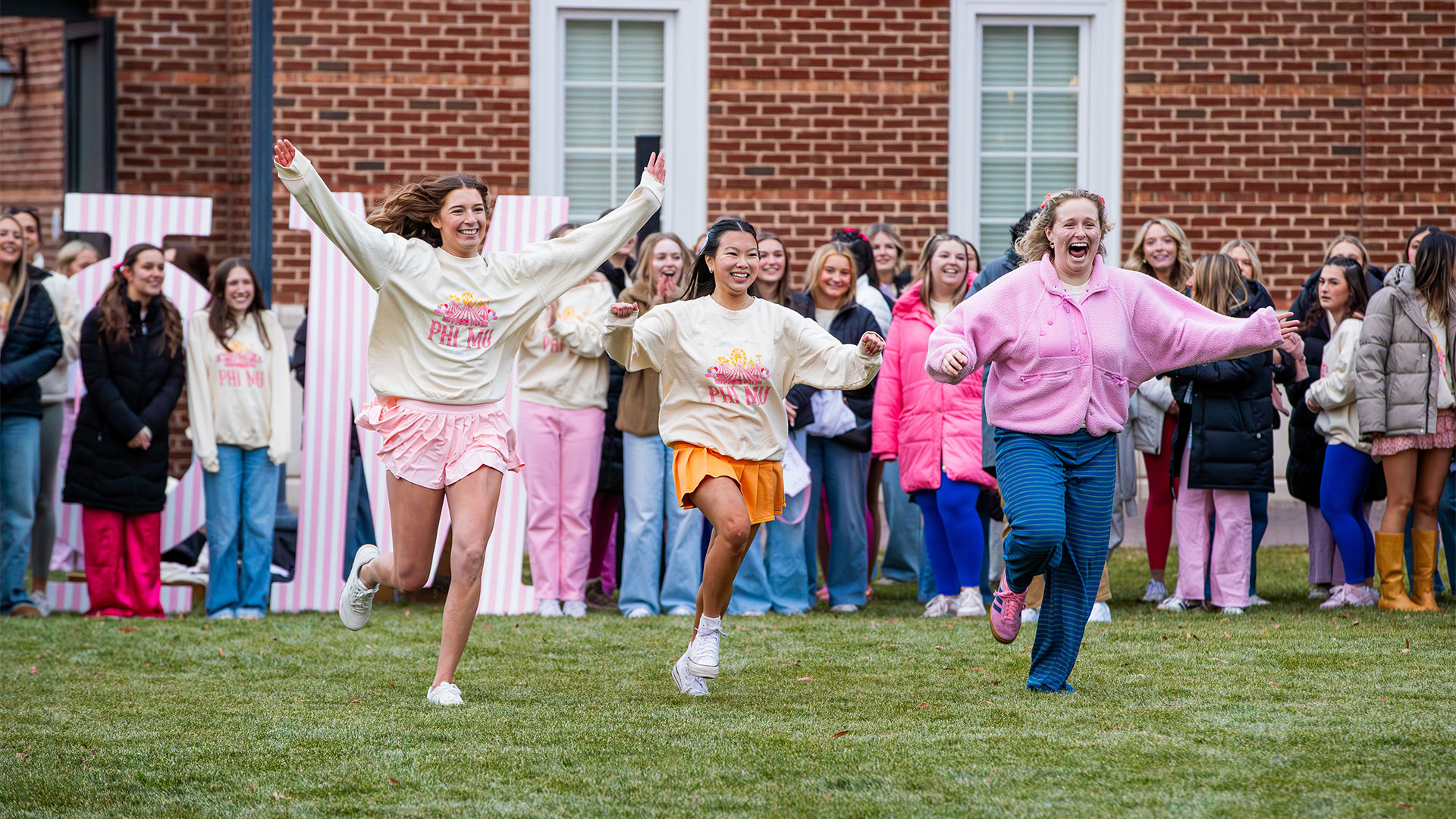 Three female students run home on Panhellenic Bid Day 2025. 