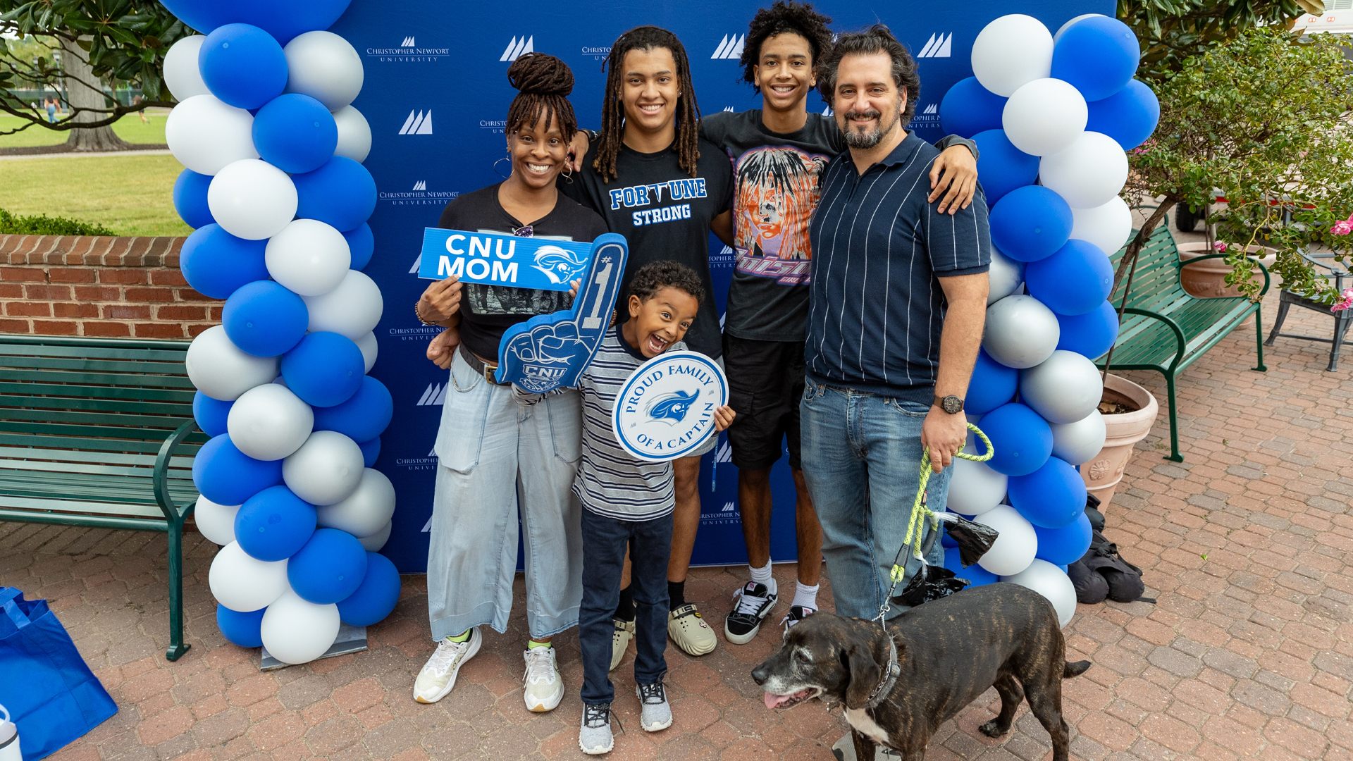 A student ambassador in a blue polo, center, talks with prospective students while giving a tour to them and their families 
